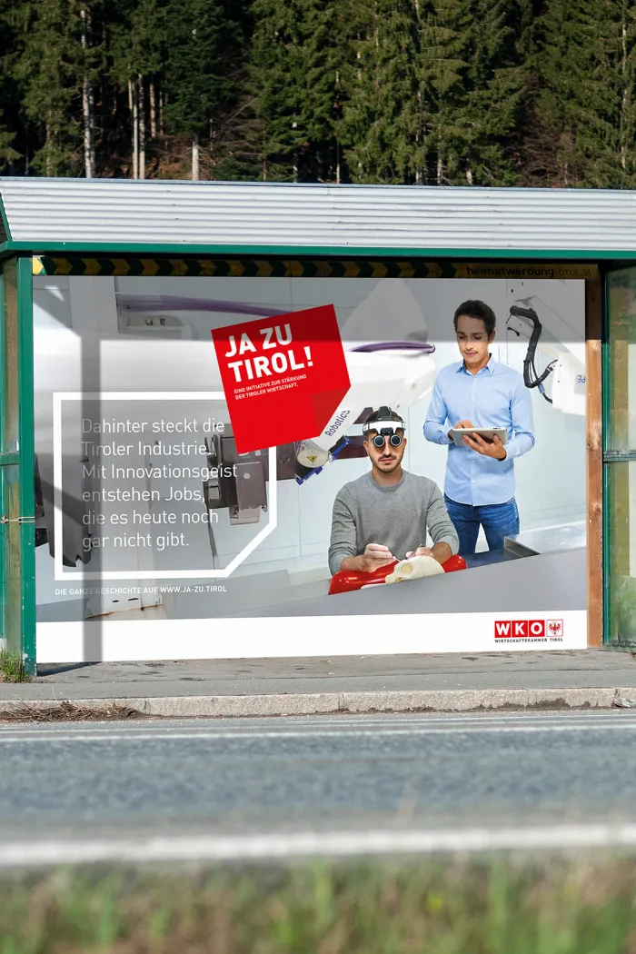 Eine Plakatfläche an einer Bushaltestelle dient als Werbefläche für das Sujet dieser Kampagne. Auf dem Plakat sind zwei Männer in der Forschung zu sehen, die die Tiroler Industrie repräsentieren, sowie ein Post-It mit der Marke.