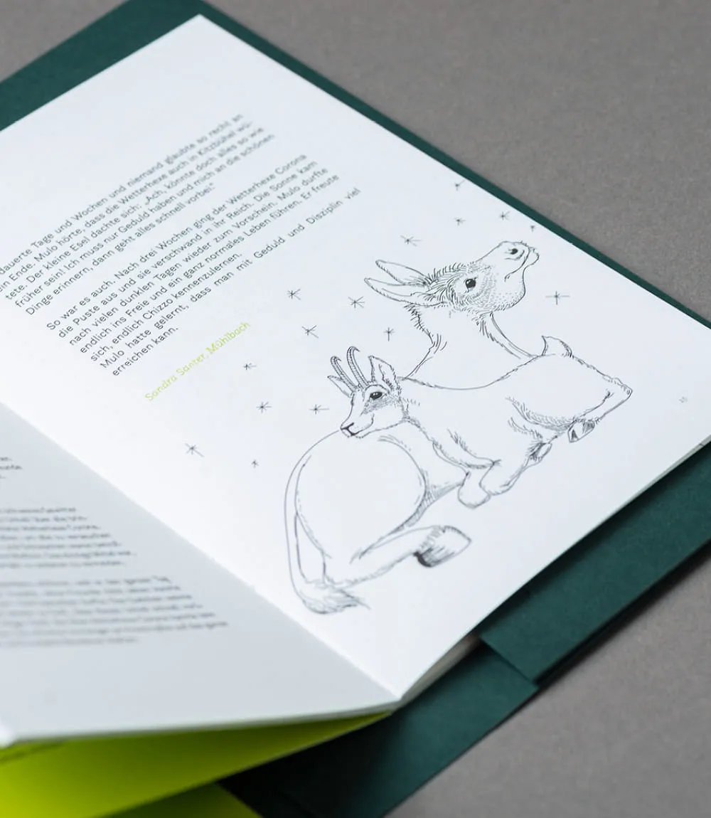 Detailaufnahme eines liebevoll gestalteten Buches mit einem persönlichen Text links und einer feinen Schwarz-Weiß-Illustration rechts: Ein Esel und eine Gams lehnen sich Rücken an Rücken aneinander, umgeben von kleinen Sternen.